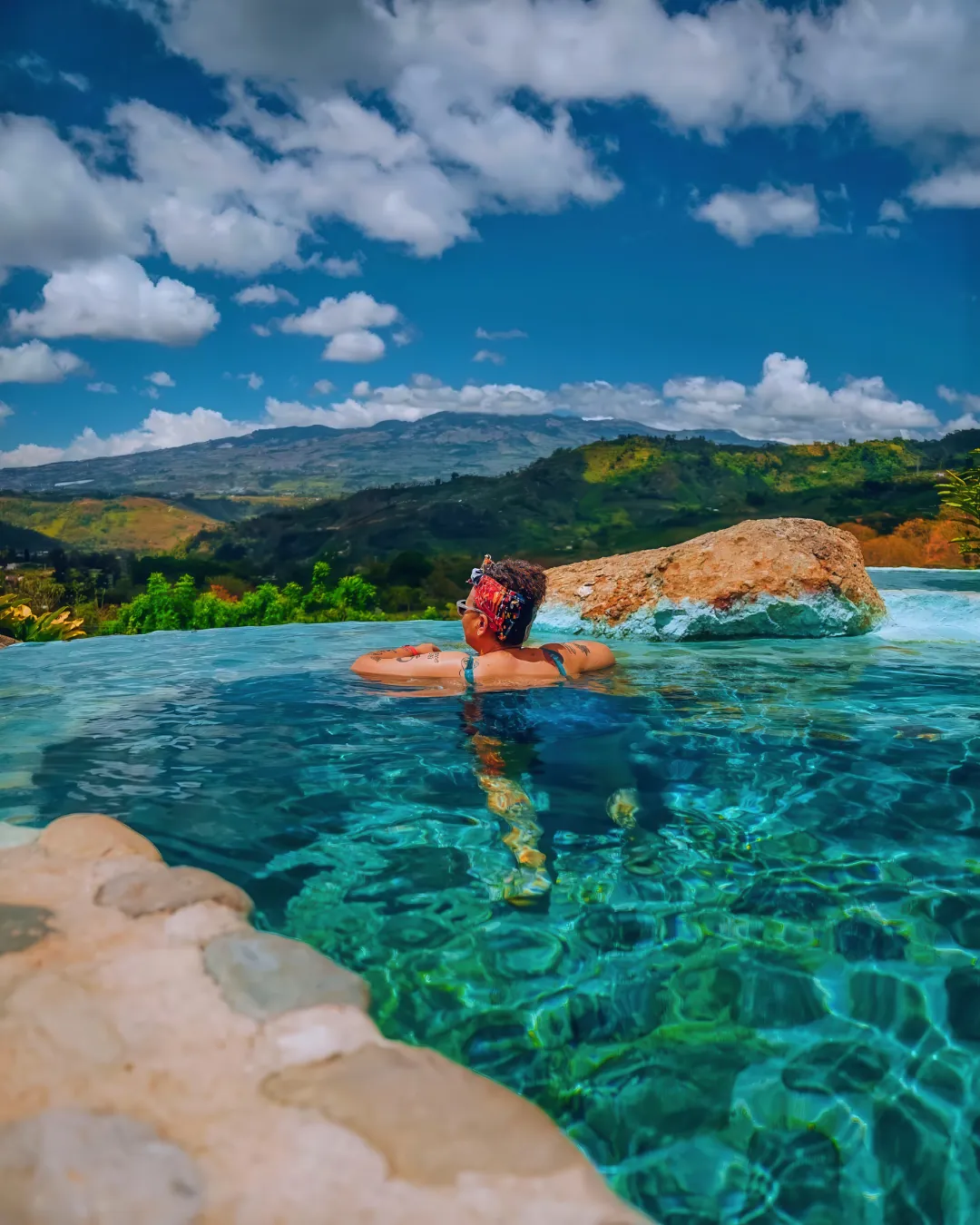 A traveler soaking in a warm mineral pool overlooking green Costa Rican mountains