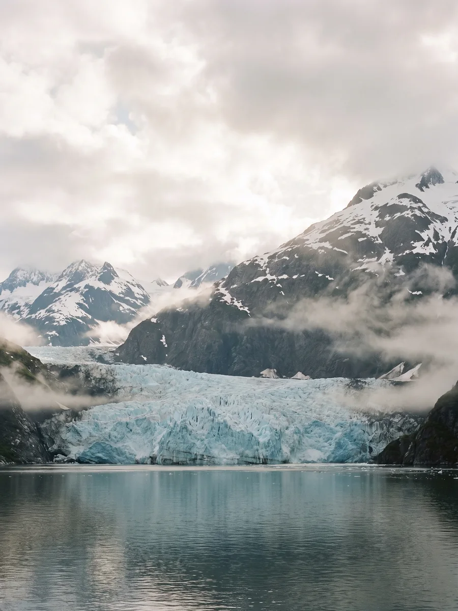 A blue tidewater glacier and snow-capped mountains in Alaska's Inside Passage