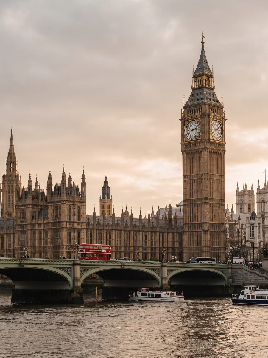 Big Ben and the Houses of Parliament beside the Thames with a red double-decker bus
