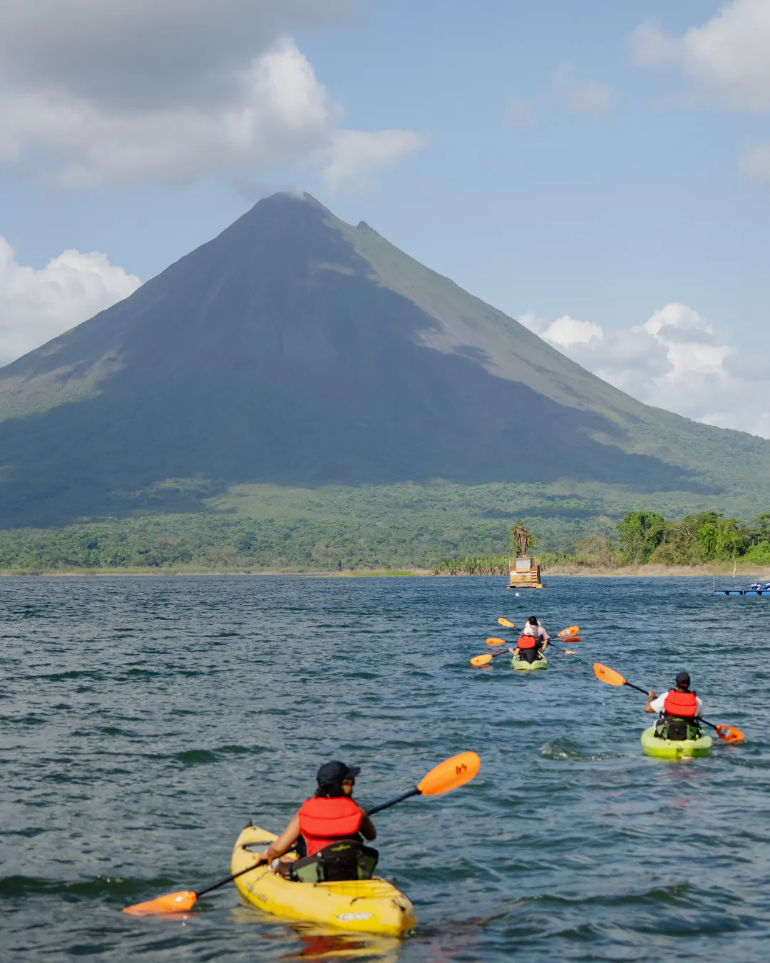 A team kayaking together on a lake beneath the Arenal volcano