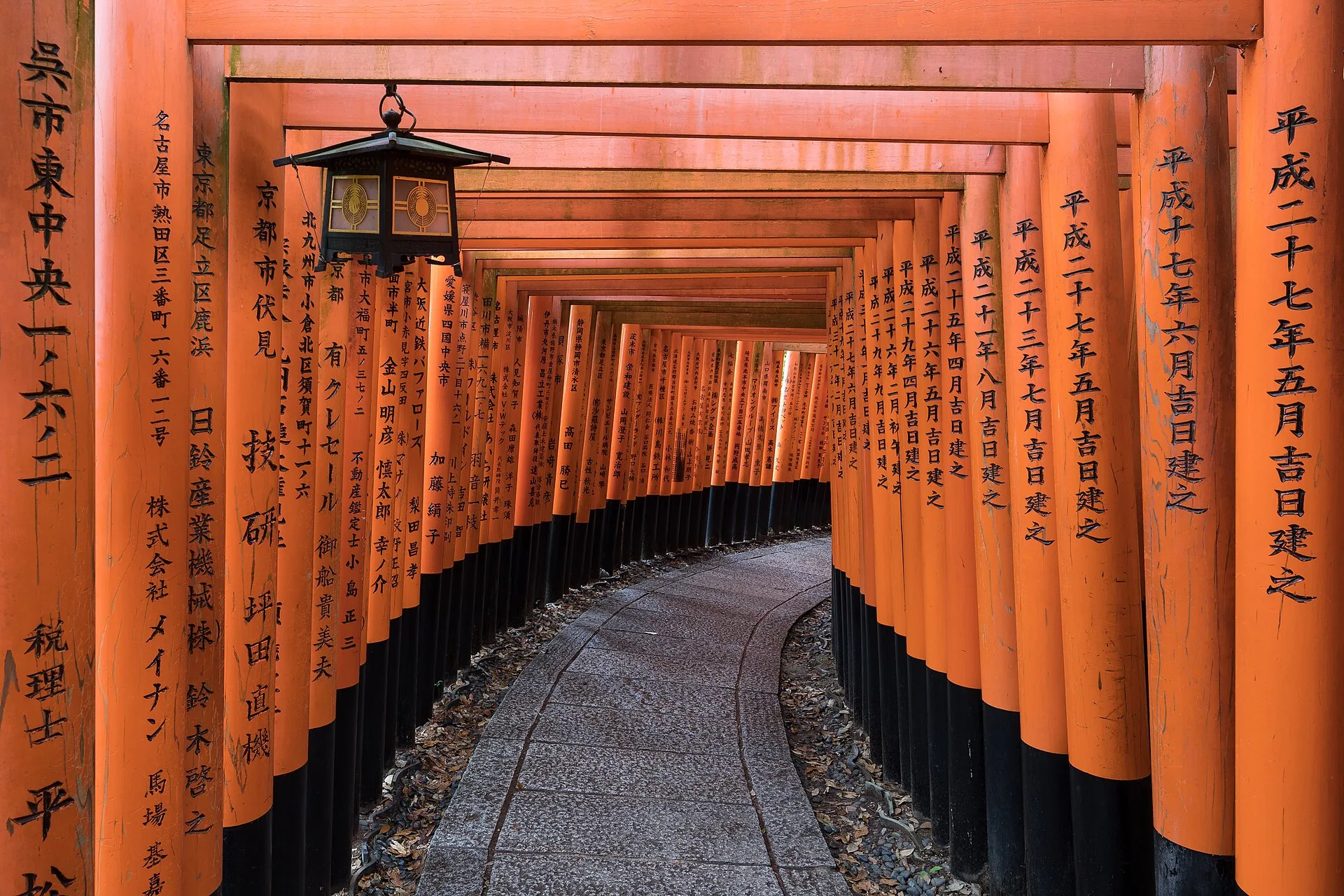 The vermilion torii gate tunnel of Fushimi Inari Shrine in Kyoto, a stone path curving through the gates