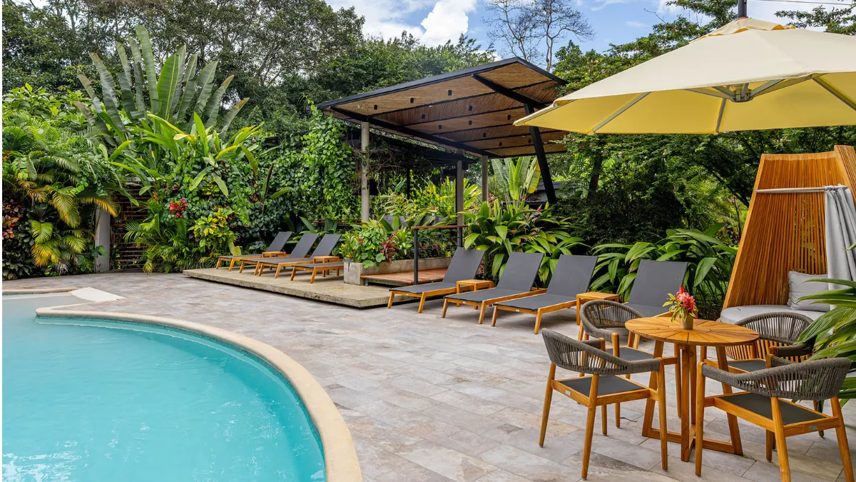 Lounge chairs and a cream umbrella beside a quiet resort pool