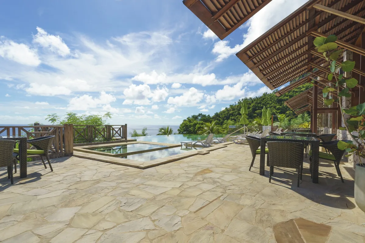 A curved pool surrounded by tropical gardens and lounge chairs at a boutique resort