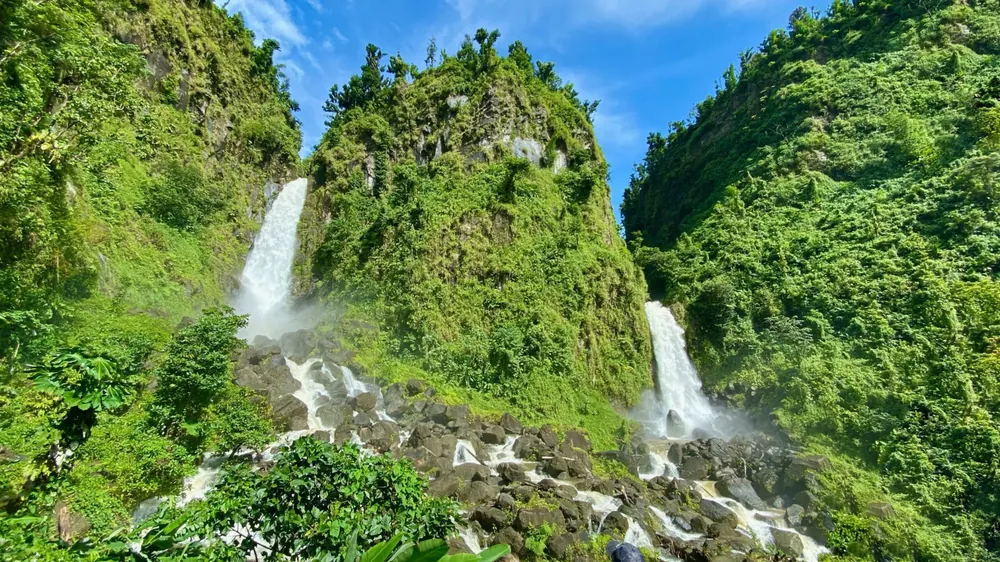A waterfall pouring through dark volcanic rock into a pool