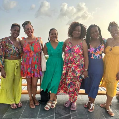 Six retreat guests in colorful dresses gathered at golden hour before the welcome dinner